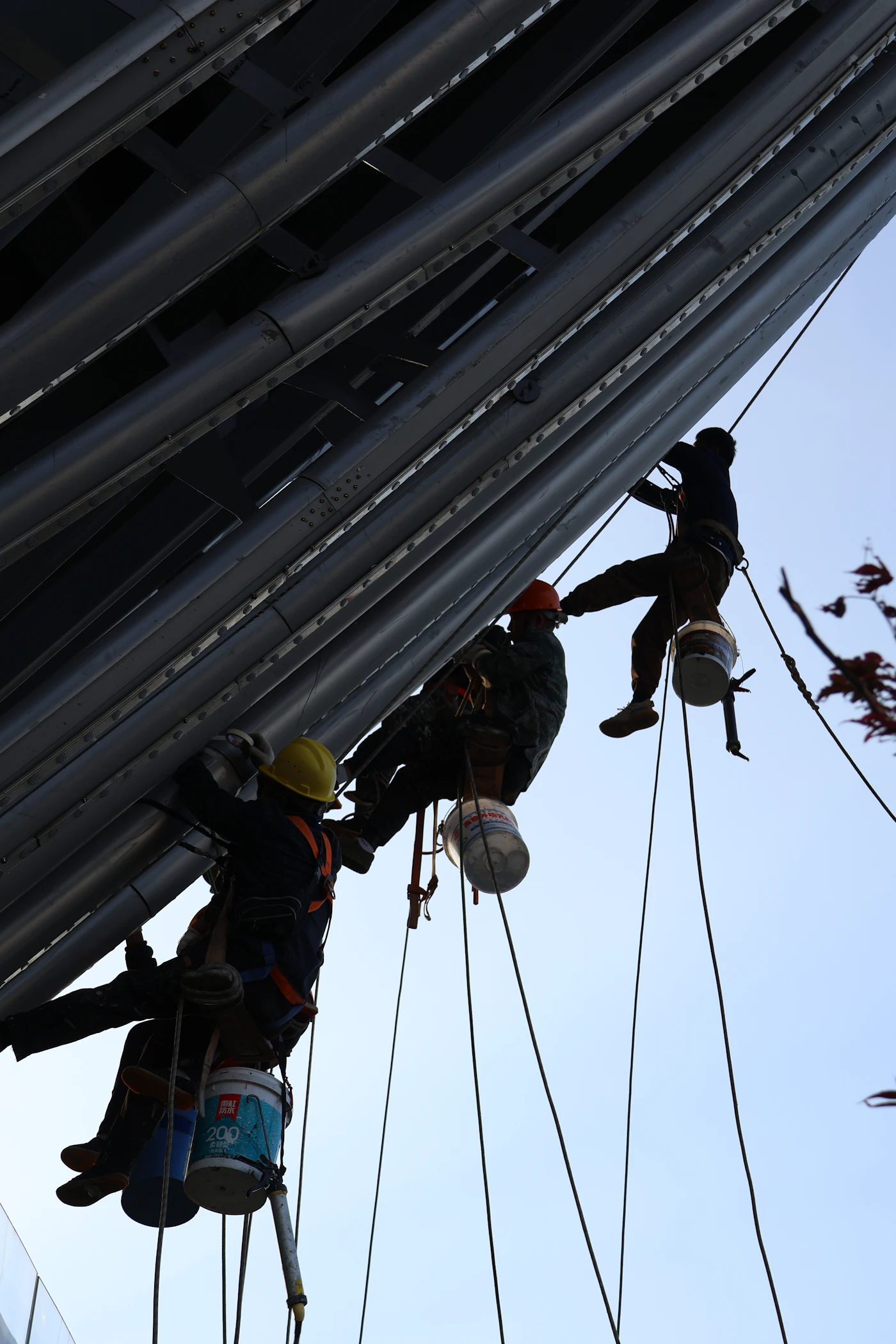 Three rope access technicians working side by side on a building exterior