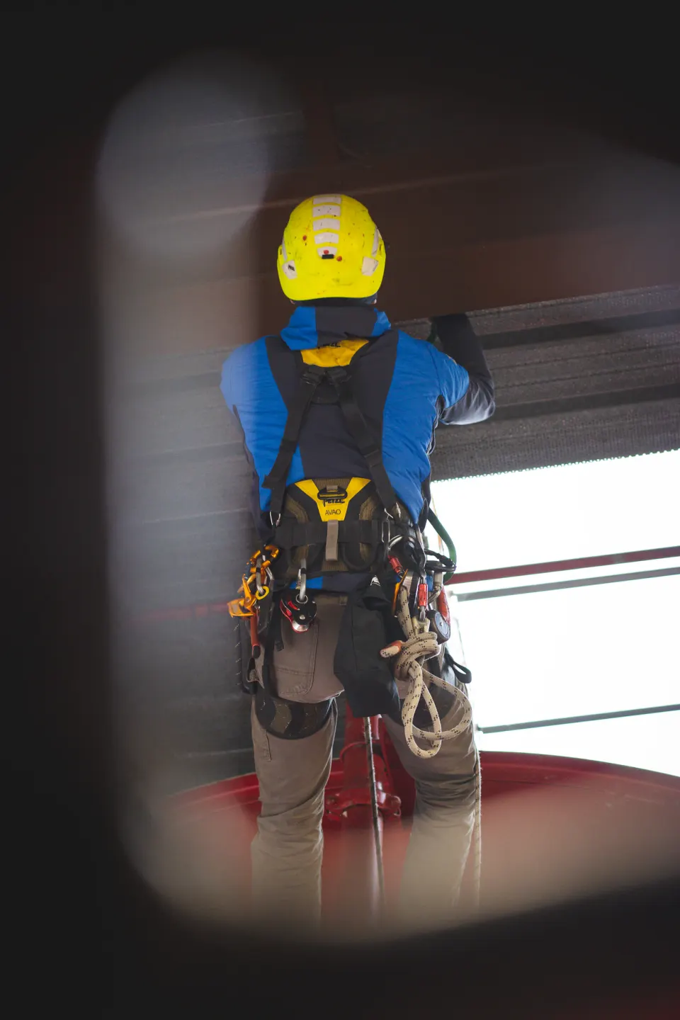Rope access technician in a yellow helmet and harness working inside an industrial structure
